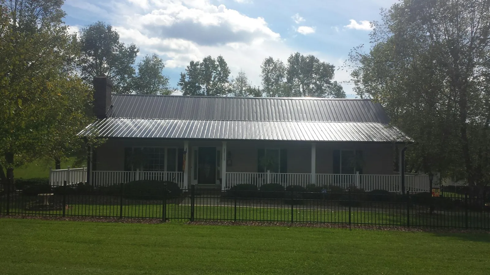 Gray metal roof on a brick ranch with a full width front porch — Gutter Guard Installation work by our crew in Charles Town