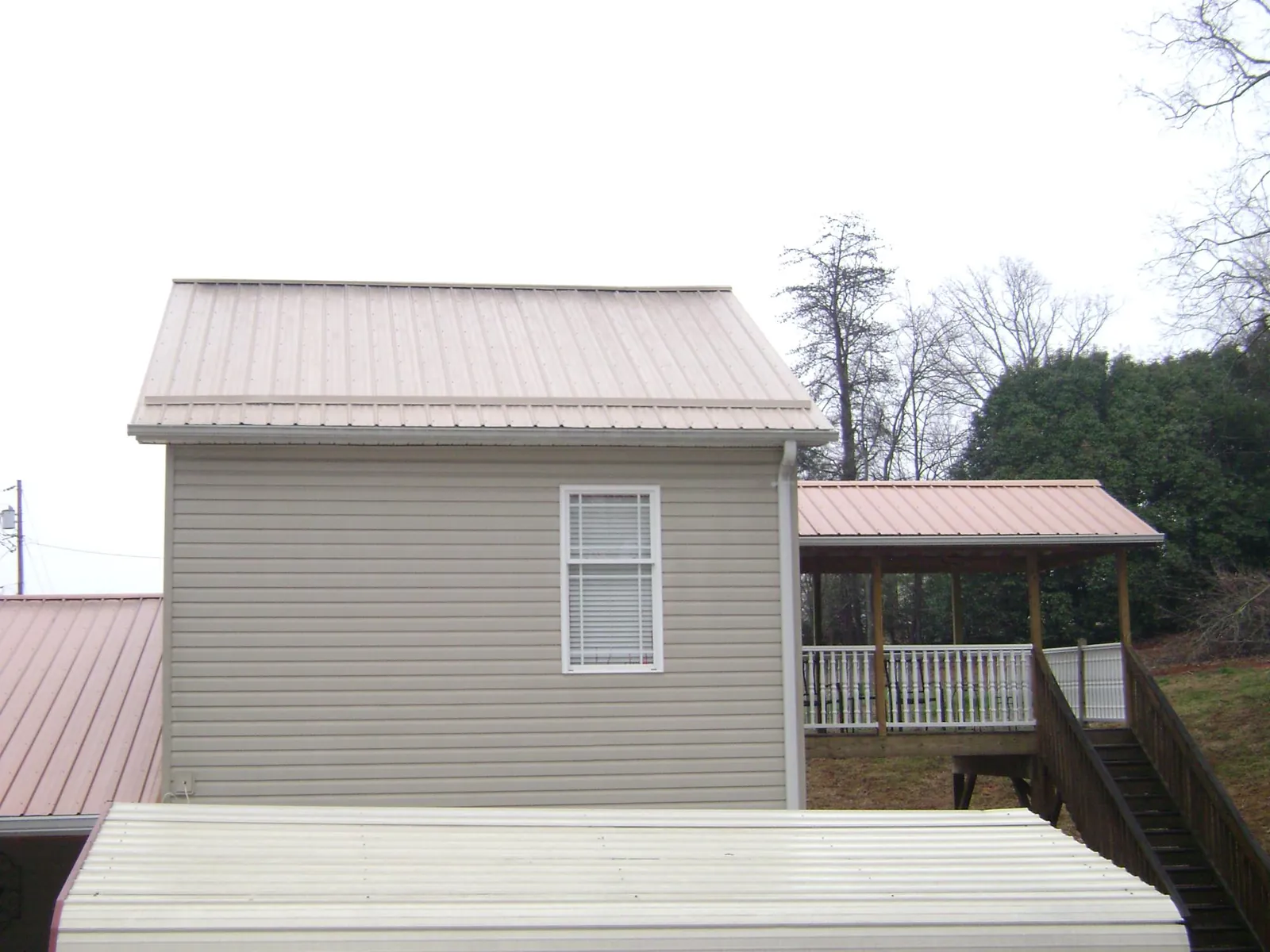 Tan metal roofs on a two story addition and attached porch, from a Roof Replacement job in Charles Town