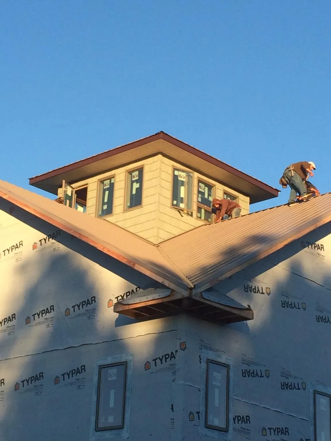 Roofers working around a rooftop cupola on a new metal roof at sunset — Roof Waterproofing in Charles Town by Roofing Brothers